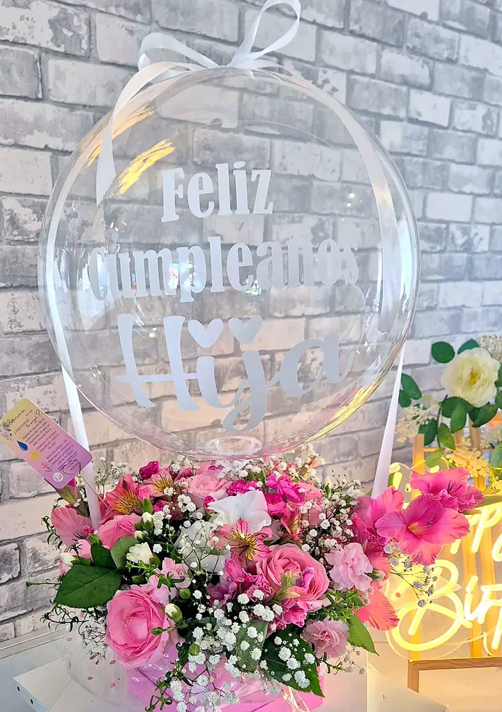 Personalised bubble balloon with a Spanish birthday message above a pink flower box